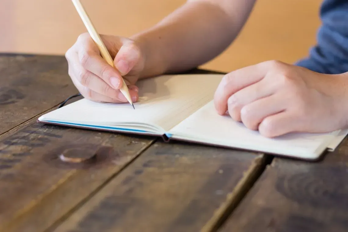 Close-up of hands writing goals in a journal