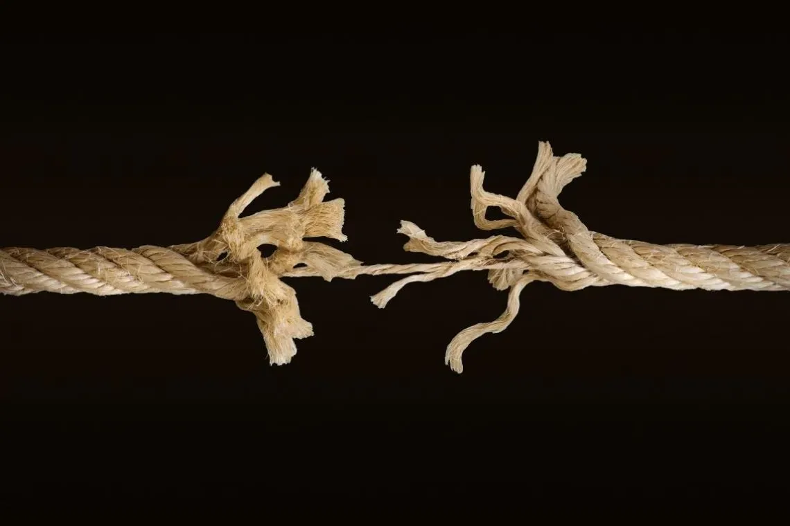 Frayed rope breaking apart against a black background