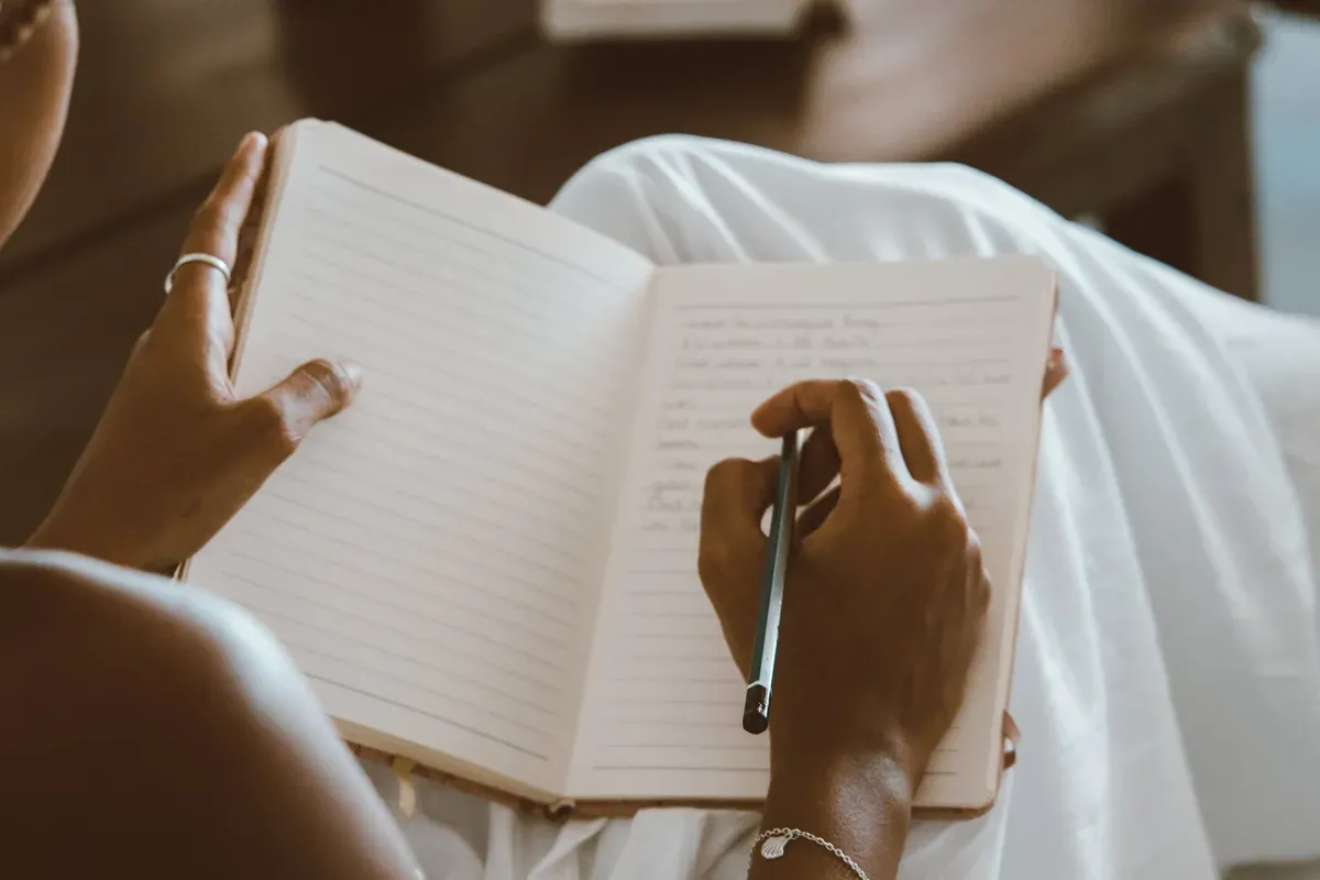 Person writing by hand in a gratitude journal