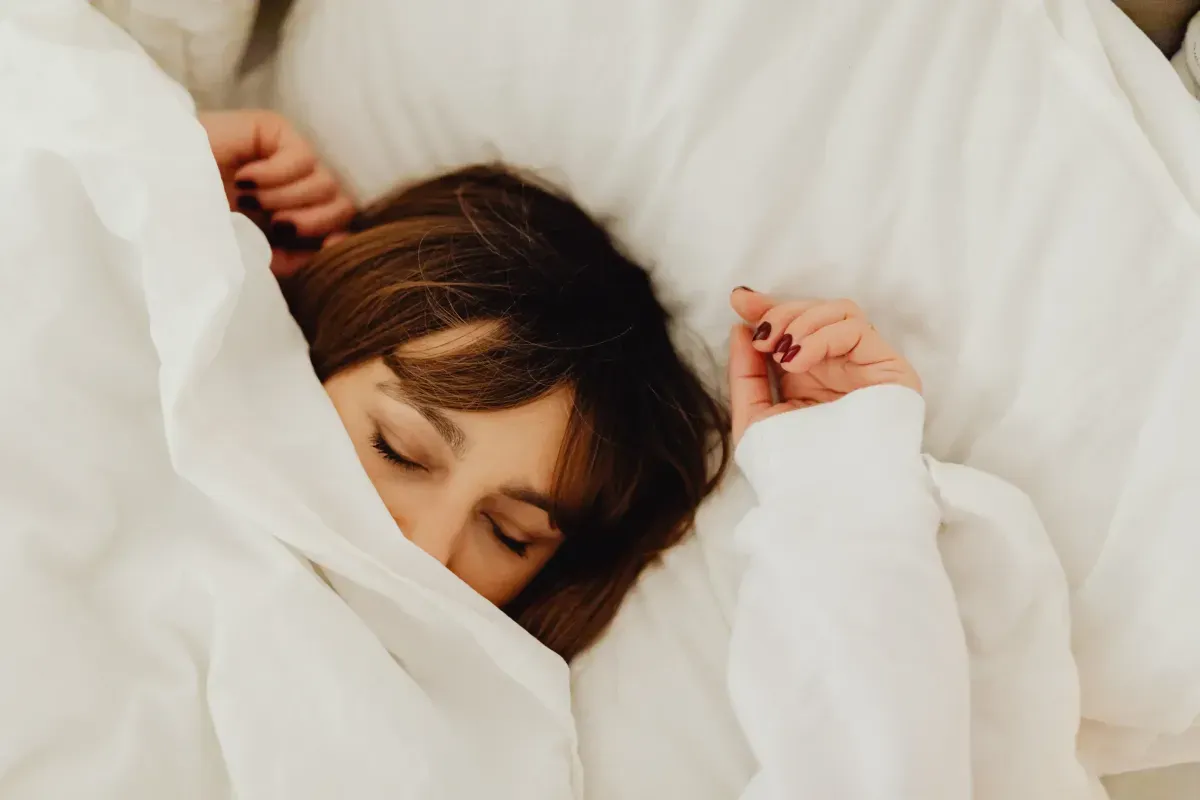 Woman cocooned in a white duvet resting peacefully in bed
