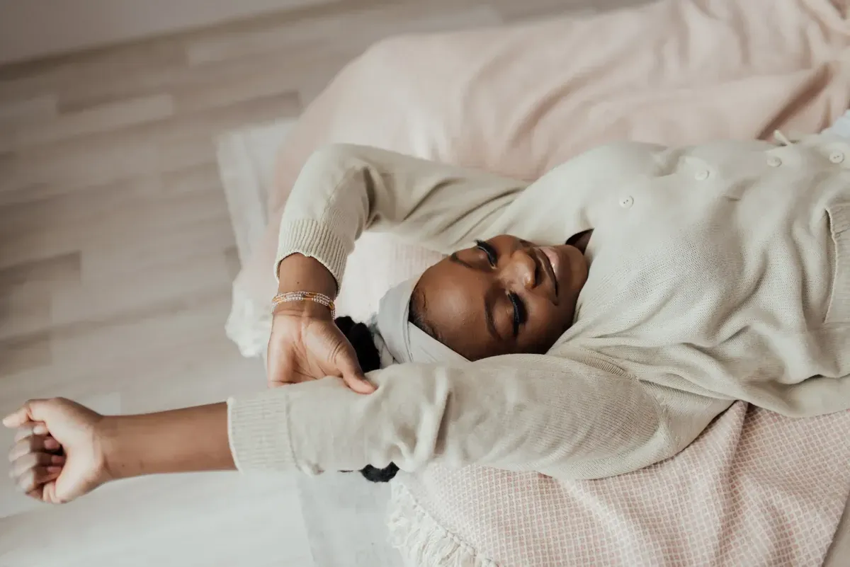 Woman stretching her arms while lying in bed
