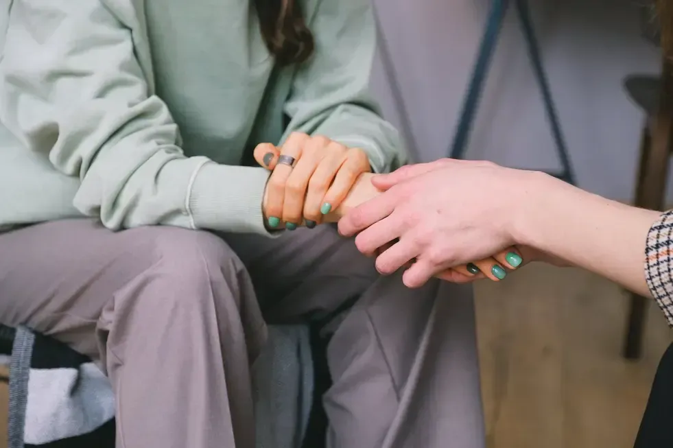 Two people holding hands in a supportive, comforting gesture
