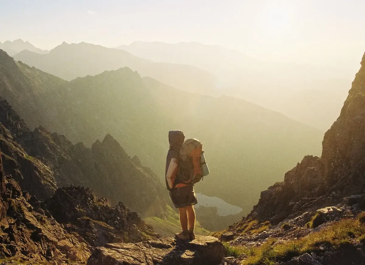Hiker with a backpack overlooking a misty mountain valley