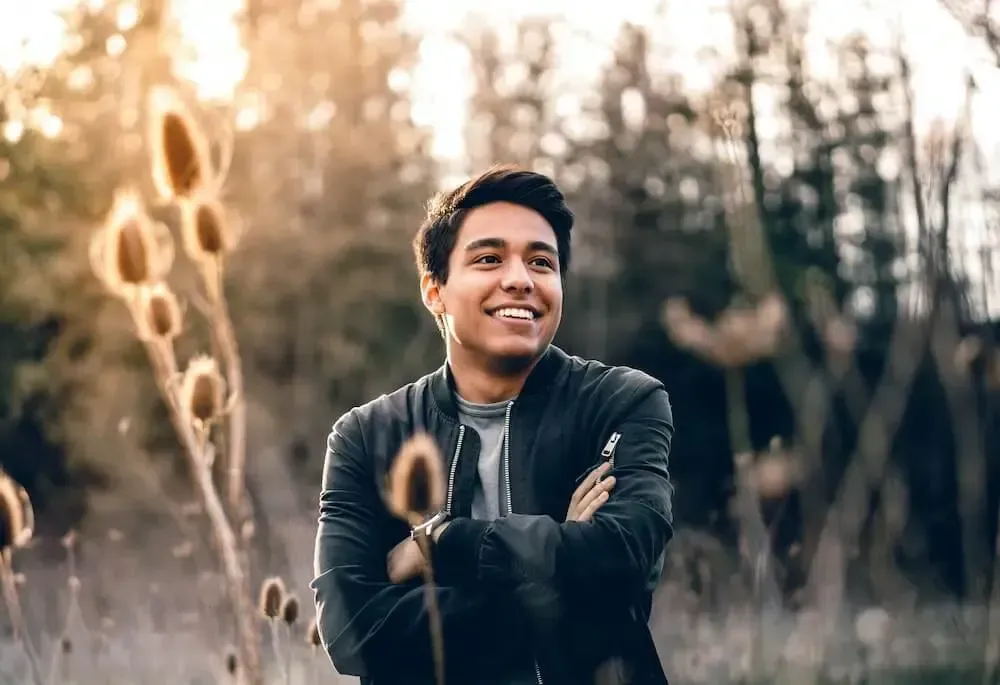 Young man smiling outdoors in a field at sunset