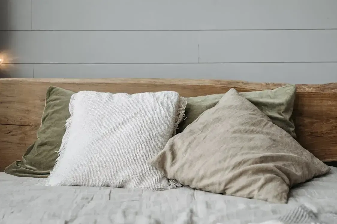 three pillows arranged on a bed with a wooden headboard