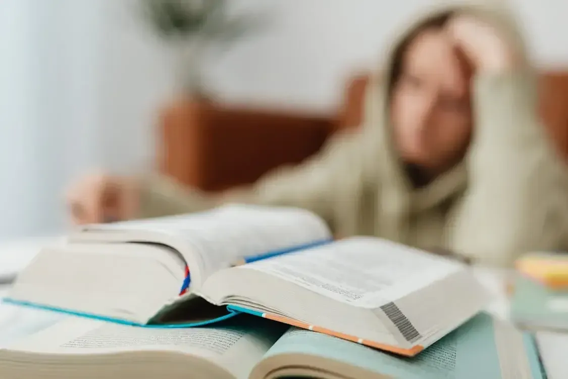 Stressed student resting head in hands over a stack of books
