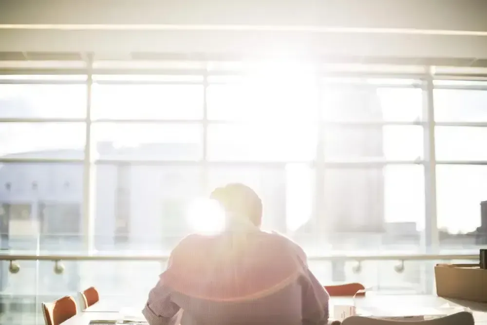Silhouette of a man sitting alone in a sunlit office