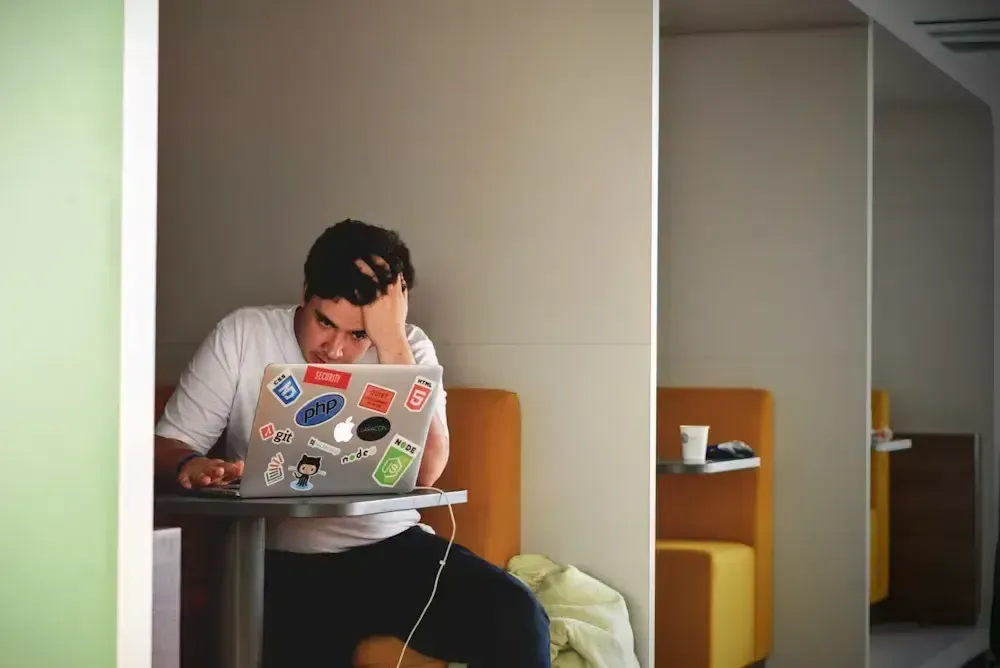 Stressed developer with head in hand staring at his laptop