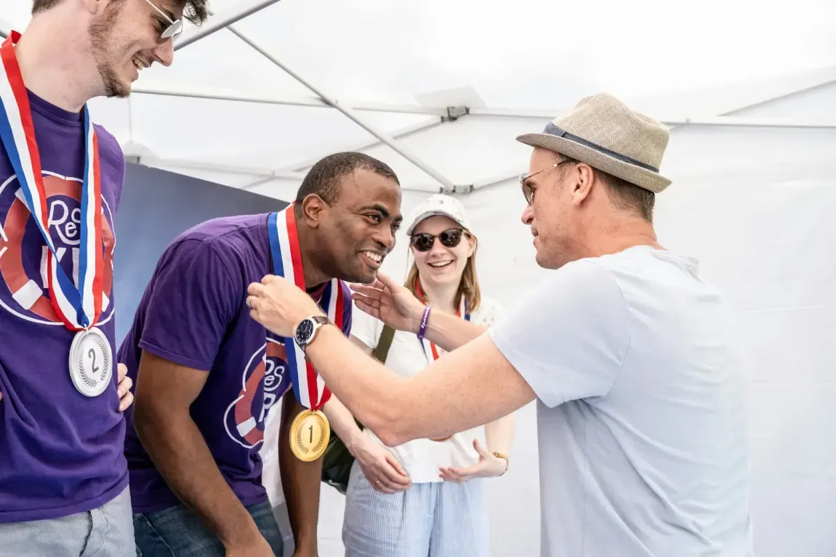 Man placing a gold medal around another man's neck at an event