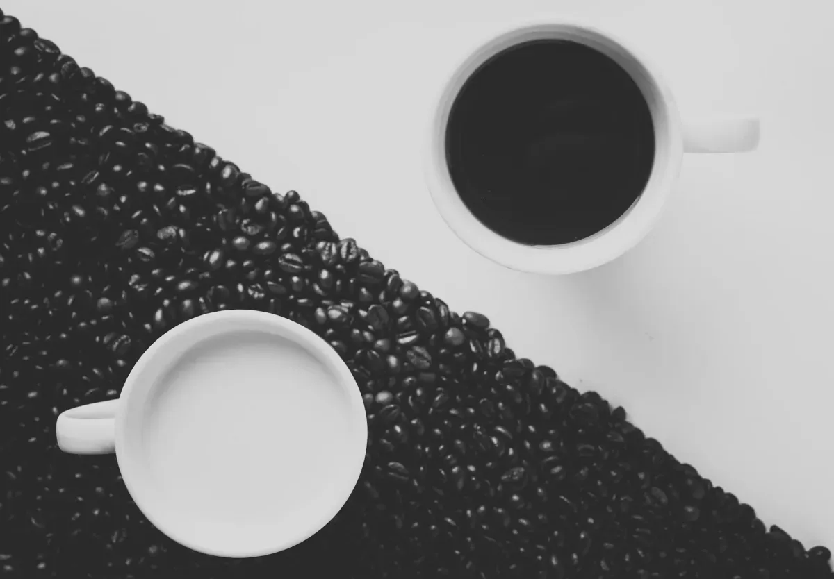 Two coffee cups surrounded by scattered coffee beans