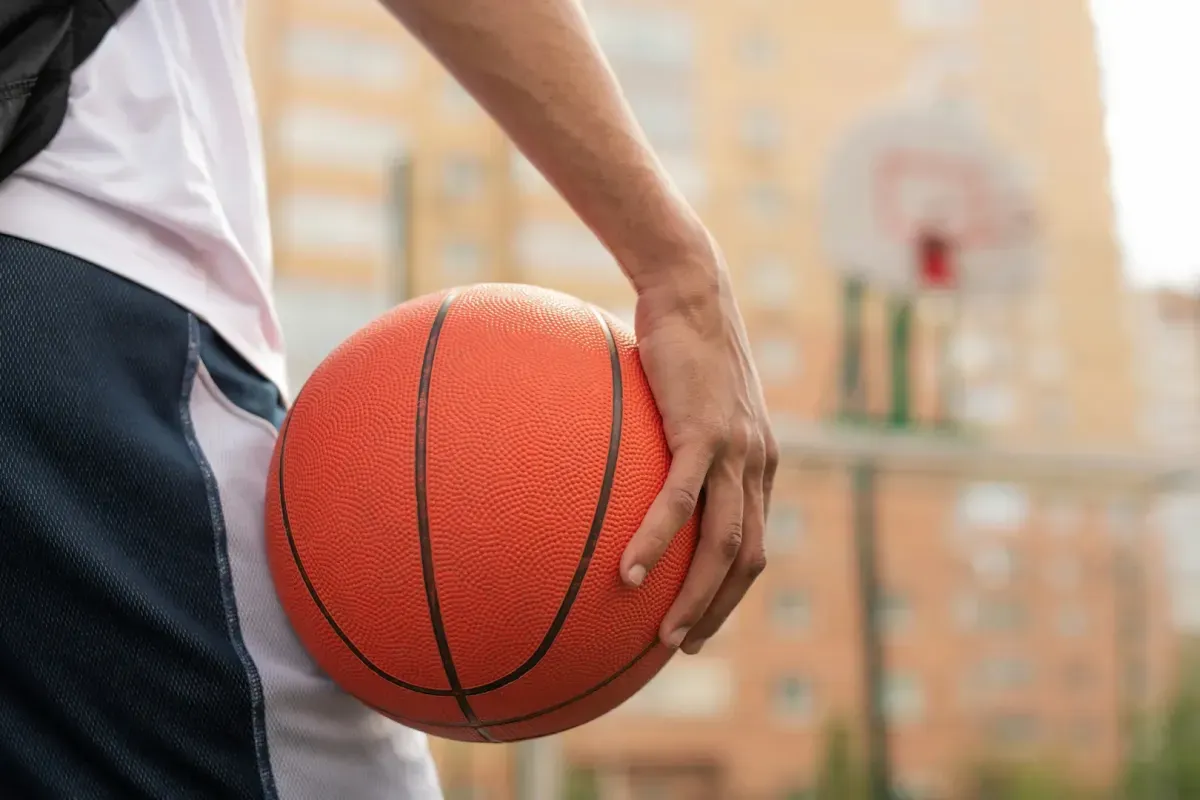 person holding a basketball on an outdoor court