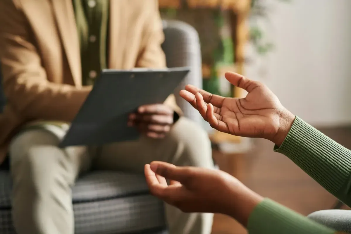 therapist taking notes while a client gestures during a session