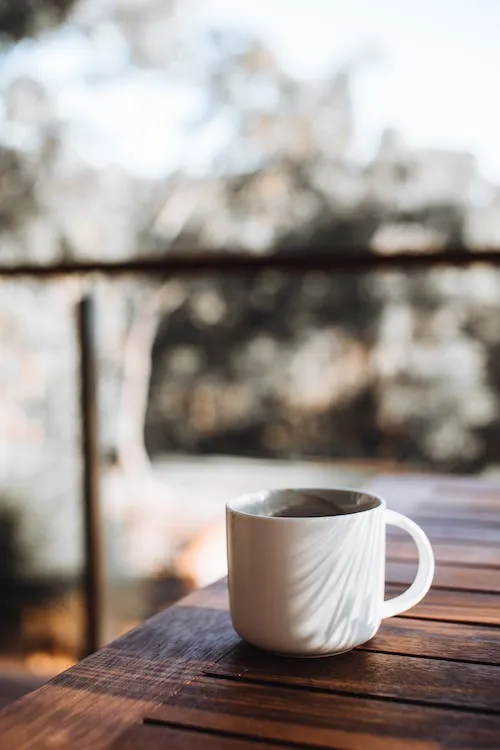 Free White ceramic cup of hot drink placed on brown wooden table on terrace Stock Photo
