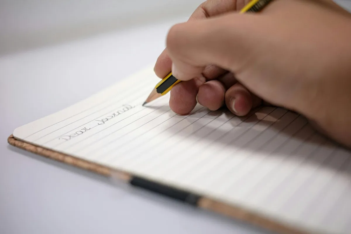Free stock image of a person journaling their thoughts on a notepad.